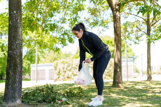Woman picking up trash in park for environmental cleanup