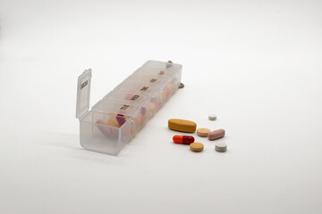 Weekly pill organizer filled with assorted pills and capsules