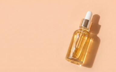 Naklejka premium Close-up of a glass serum bottle with a dropper on a peach background