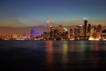 Toronto skyline at dusk with illuminated city lights reflecting on the water, vibrant urban night view. g.