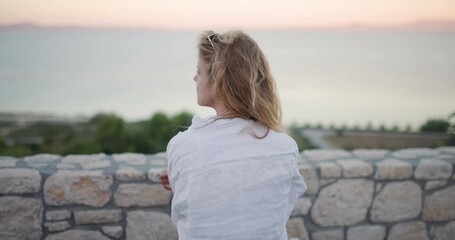 Woman enjoying a serene sunset view by the seaside with beautiful hair blowing in the breeze