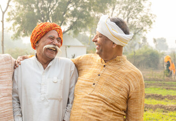 Happy rural indian farmer friends laughing. Smiling senior male friends wearing traditional kurta...