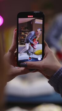 Closeup View Of Phone Display Filming Active Teenager Performing Guitar And Dance Moves On Sofa Creating Fun Dynamic Social Media Style Home Video