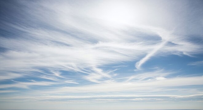 Wispy cirrus clouds paint the expansive blue sky with delicate strokes, creating a serene and ethereal atmosphere high above the earth on a bright sunny day