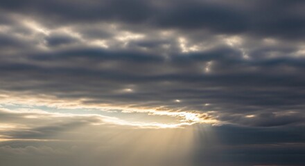 Sun rays shining through dark clouds, creating a dramatic and ethereal atmosphere in the sky during sunset or sunrise