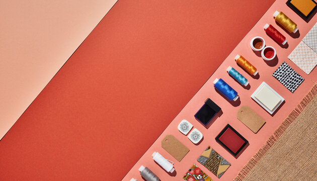 Vibrant crafting scene with sewing threads, fabric swatches, and charming accessories arranged on a coral backdrop, perfect for creative projects and design mockups - Powered by Adobe