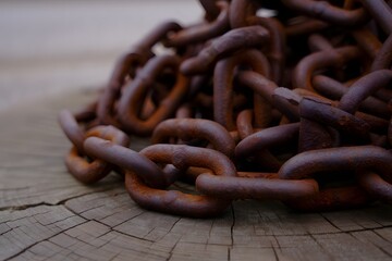 Fototapeta premium Rusty chain links on weathered wood show strength and age with a close up view