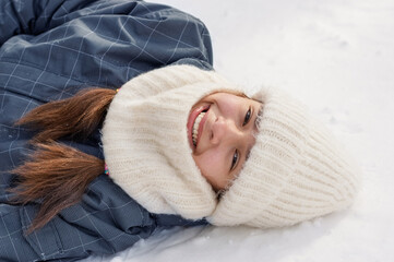 Girl lying on snowy ground  and enjoying winter fun. Close-up