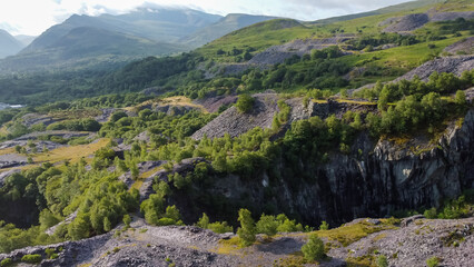 Aerial view over slate quarry slopes with distant Snowdonia mountains