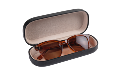 Sunglasses with brown frames and lenses are inside an open black case with a beige interior on white and transparent