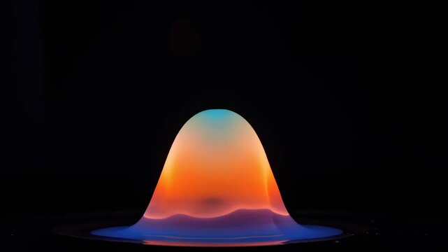 A vibrant, bell-shaped flame with distinct blue, orange, and cyan color layers against a dark background, showcasing combustion.