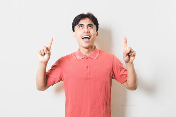 Young man pointing upward with an enthusiastic look, suggesting ideas, inspiration, notifications, tips, or important highlights for advertising and promotional content.