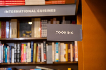 View of cooking section sign in bookstore with shelves of books.