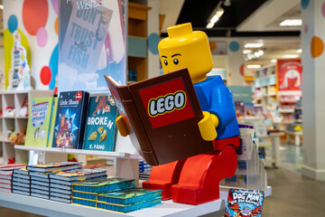 Obraz premium View of Lego figure reading a book in children's bookstore display. Toronto, Canada - December 3, 2025.