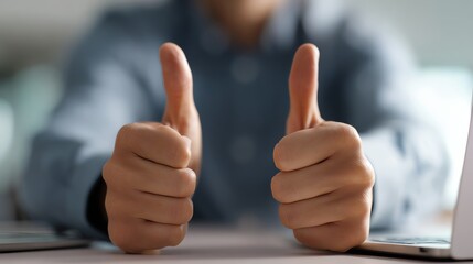 A close-up of two hands giving a thumbs up gesture, symbolizing approval, success, and positive feedback in a professional setting, conveying confidence and collaboration.