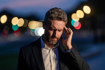 Business man in suit with headache. Sad man got migraine touches his head because of pain. Tired businessman has stress. Tired businessman is working overtime and has headache