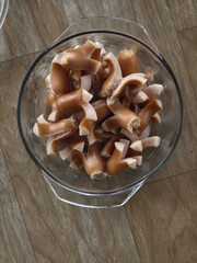 Top view of glass bowl with sliced pig ear, pork meat offal ingredient for delicious food dish....