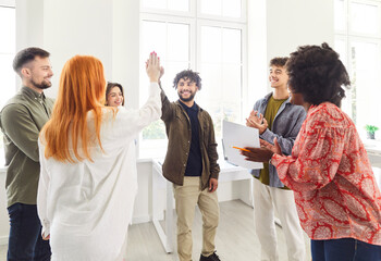 Happy colleagues working in an office, celebrating success by giving each other high fives and applauding. The business team is in a meeting, enjoying their achievements and teamwork.