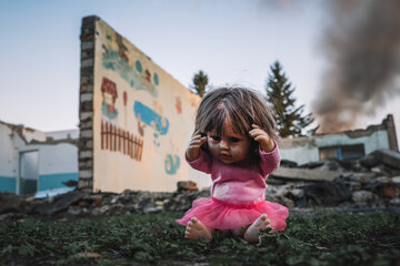 the concept of destroying childhood by war. frightened doll against the background of a tank and a burnt-out building. concept of suffering of children and civilians in war.