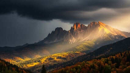 Fototapeta premium Sunlight breaks through storm clouds over an autumn mountain landscape.