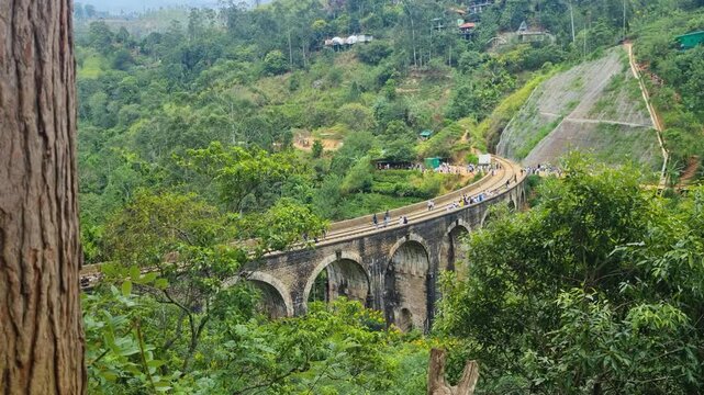 Aerial perspective of the Nine Arch Bridge in Ella Sri Lanka revealing the graceful colonial railway arches rising above dense green highland jungle and misty tropical scenery