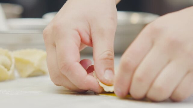Chef's hands shaping, cutting the dough and filling the Ravioli with artisanal technique in a professional kitchen.
