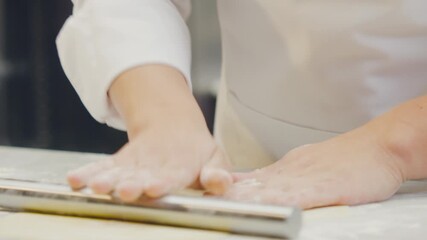 Chef's hands shaping and cutting ravioli dough using artisanal techniques in a professional kitchen.