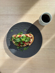 A cup of coffee and toasted bread with bacon and spinach.