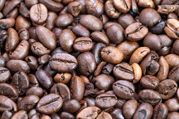 Coffee bean closeup, Texture and sheen of roasted coffee beans revealed, Macro photograph highlighting glossy appearance and textured surface of freshly roasted coffee beans
