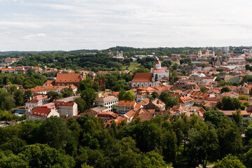 Fototapeta premium Beautiful city streets on a sunny summer day. Historic buildings among green trees in a European city. A panoramic view of the historic city from a bird's-eye perspective. June 1, 2025, Vilnius, Lithu