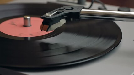 A close-up view of a vintage record player with a black vinyl record spinning on the turntable, featuring the tonearm and stylus. - Powered by Adobe
