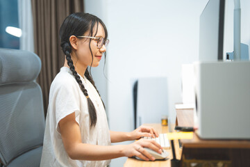 Young adult asian woman gen z freelance using desktop computer upskill tech assistance ai chatbot at home office
