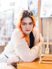 Asian happy beautiful cheerful portrait young woman light orange long hair smiling sitting art themed coffee shop cafe, natural wooden textures create joyful relaxation travel holidays lifestyle.
