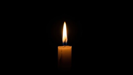 Solitary candle flame illuminates dark room with warm gentle glow