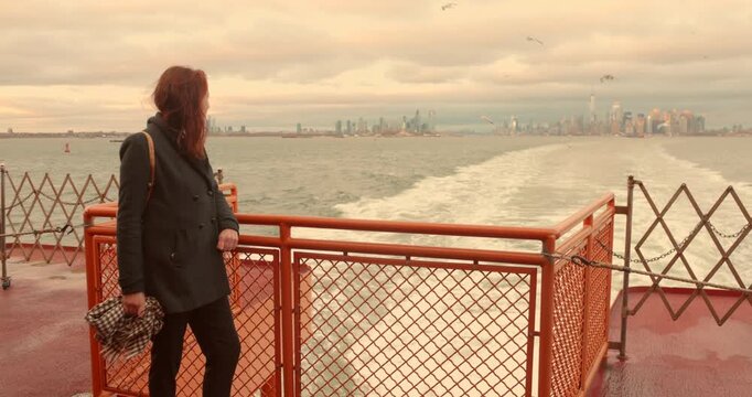 Woman on NYC ferry enjoying view of Manhattan skyline, contemplative mood
