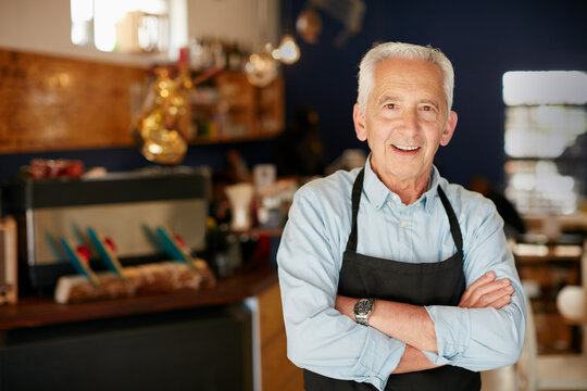 Mature man, portrait and small business with confidence in cafe for bakery startup in restaurant. Male person, apron or smile with arms crossed in cafeteria or deli for entrepreneurship or service - Powered by Adobe