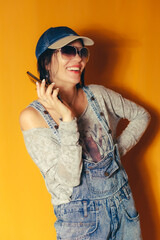 Fashionable woman in denim outfit talking on a smartphone and smiling