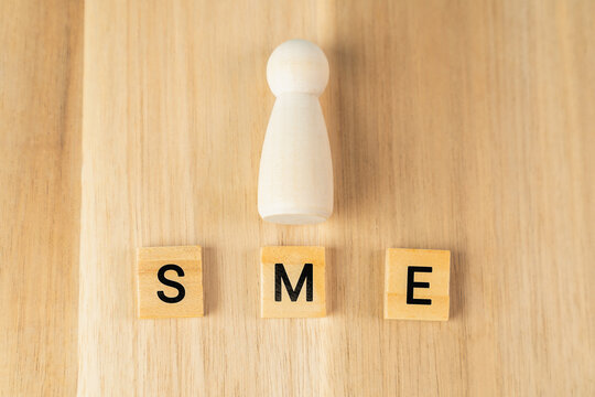 Small business, SME text on wooden cube block background.