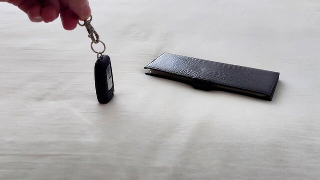 Wallet and car key rest on a light tabletop as soft daylight highlights texture and shape, creating a simple everyday moment with a calm, organized feel