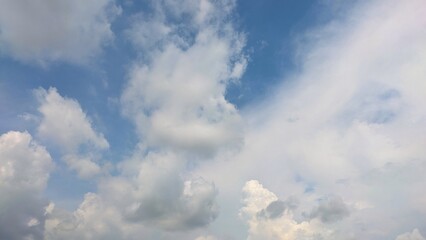 A dynamic backdrop of bright blue sky with fluffy white and gray clouds on a beautiful sunny day.