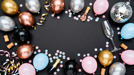 New Year party celebration background frame with luxury metallic balloons, confetti, and disco ball on a black surface with ample copy space.