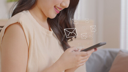 Close up of Asian woman hand smiling while reading messages on her smartphone with floating email icons