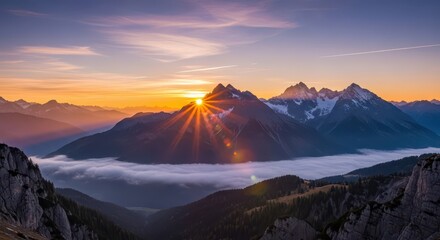 Brilliant sunrise bursts over snowcapped mountain peaks above a low valley fog layer