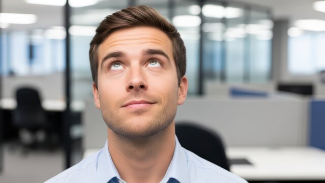 Young male in office looking upward with thoughtful expression - Powered by Adobe