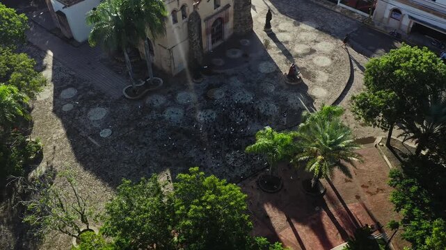 Aerial drone view of the San Dionisio Church in Hig&uuml;ey. The historic colonial building features a tiled roof and brick facade, situated in a tree-lined plaza in the Dominican Republic