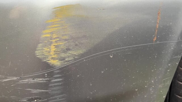 Close-up video of heavy scratch damage on a car&rsquo;s front bumper. Visible paint scrapes, scuff marks, and surface defects.