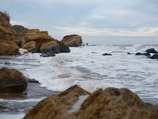 Low Angle Sea Foam and Layered Rocks
