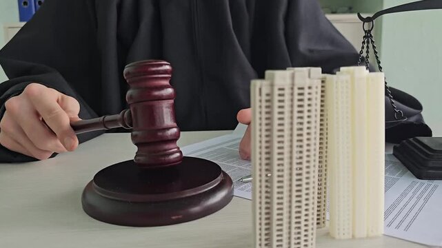 Judge presides over court session with gavel, documents, and model building on the table