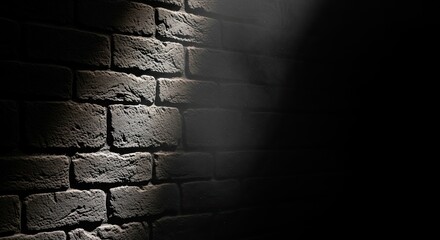 Dramatic spotlight illuminates a textured brick wall creating a stark contrast between light and shadow for atmospheric backgrounds and designs