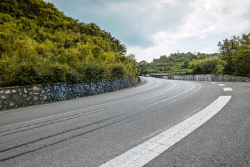 Empty winding asphalt road and green mountain landscape.